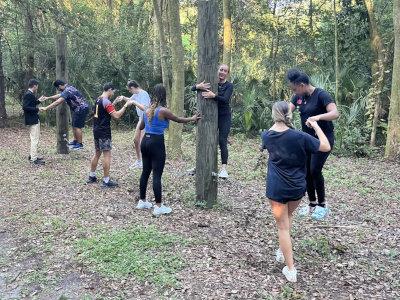 Students in wood trail enlacing their hands around trees